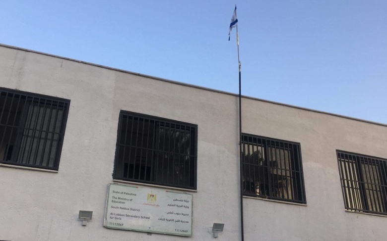 The occupation raises the flag of Israel over a school south of Nablus